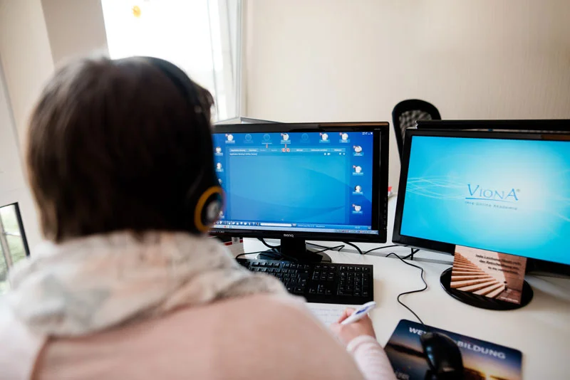 eine Frau, die an einem Schreibtisch mit zwei Computermonitoren sitzt