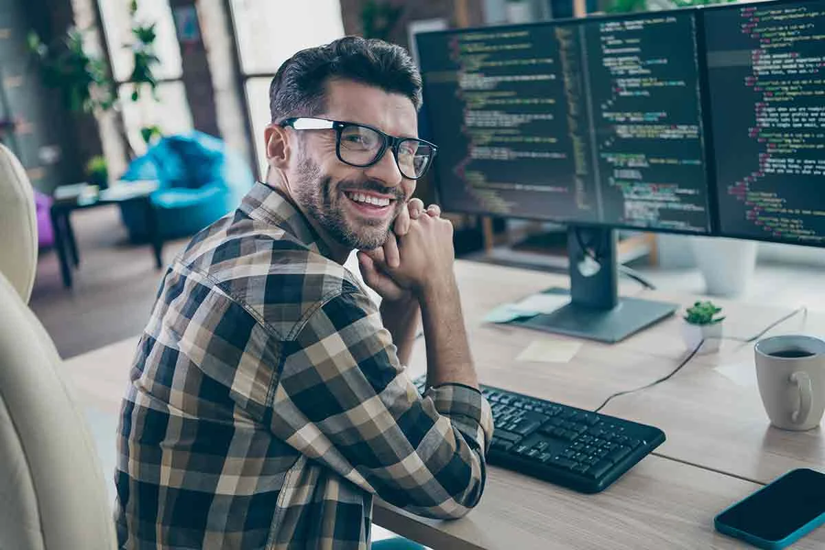 ein Mann in der Brille sitzt an einem Schreibtisch mit einem Computer